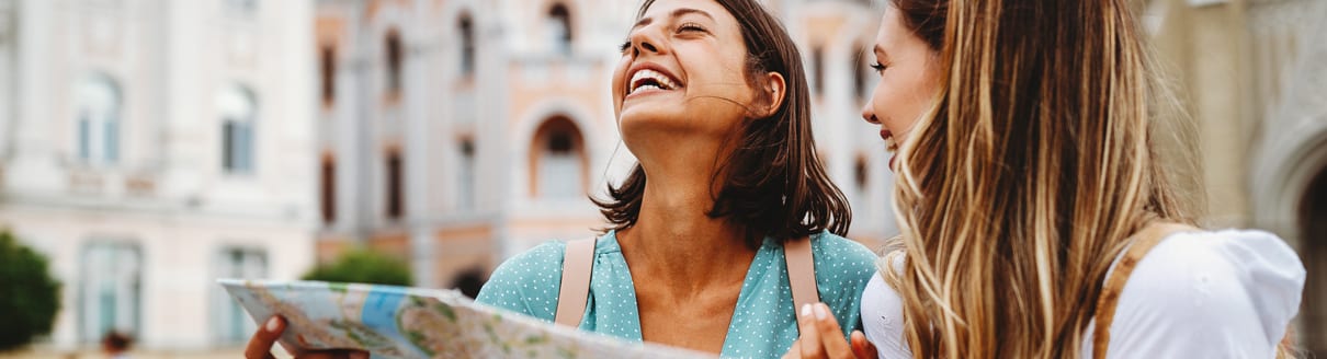 Ragazze che visitano la città e ridono guardando una mappa della città